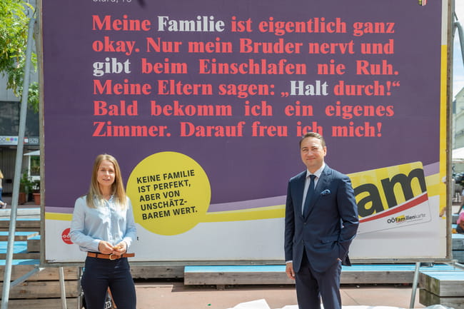 Familienreferent LH-Stv. Dr. Manfred Haimbuchner und Karin Fuchs von der Werbeagentur upart vor einem Plakatständer mit einem Sujet der Familienkampagne 